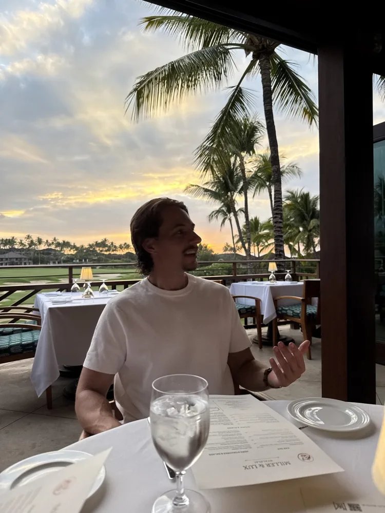 Jack talking at a dinner table at sunset